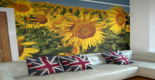 carta-da-parati una colorata carta da parati con girasoli stampati che sembrano dipinti come sfondo per un salotto con cuscini con la bandiera inglese